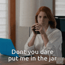 a woman sitting at a desk with a laptop and a cup of coffee says " dont you dare put me in the jar