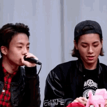 a man is singing into a microphone while another man is holding a stuffed animal .