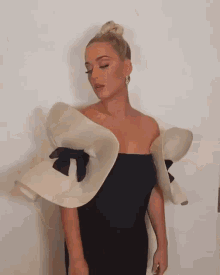 a woman wearing a black dress with white ruffled sleeves and a black bow