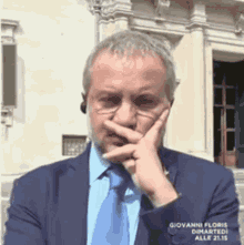 a man in a suit and tie covering his mouth with his finger