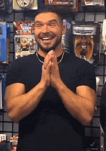 a man in a black shirt is smiling with his hands folded in front of a wall with wwe toys on it