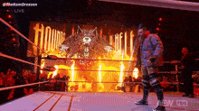a wrestler is walking out of a wrestling ring in front of a large screen that says hounds of hell .
