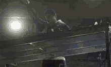 a man in a hat is standing on a stage with a light shining on him