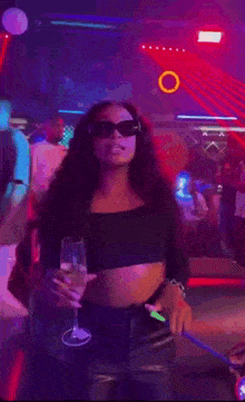 a woman is holding a glass of wine in a nightclub .