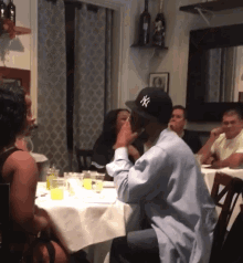 a man wearing a ny hat is sitting at a table