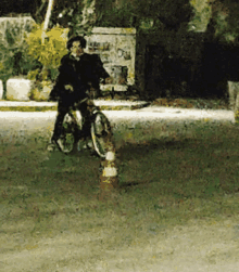 a painting of a person riding a bike with a cone in the grass