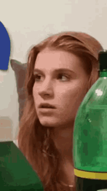 a woman is sitting next to a bottle of soda