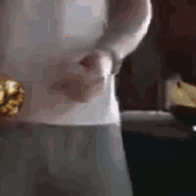 a person is holding a piece of popcorn in their hand while standing in front of a glass of water .