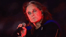 a man with long hair is singing into a microphone with red eyes .
