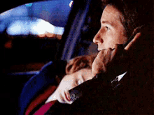 a man is talking on a cell phone while a woman sleeps in the back seat of a car