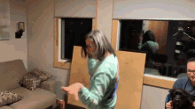 a woman in a green shirt is standing in front of a couch