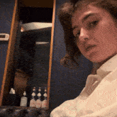 a woman in a white shirt is sitting in front of a bottle of lotion