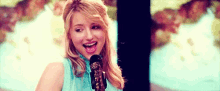a woman is singing into a microphone while holding a guitar .