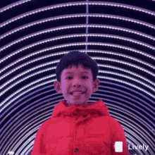 a young boy wearing a red jacket is smiling in front of a tunnel of lights