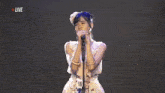 a woman is singing into a microphone on a stage in front of a crowd .