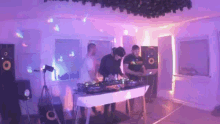 a group of people are standing around a table in a room playing music .