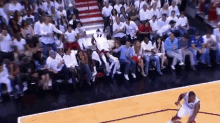 a basketball player dribbles the ball in front of a crowd of people
