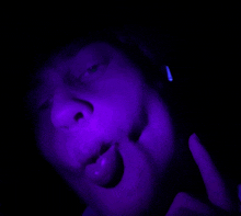 a person 's face is lit up with purple lights