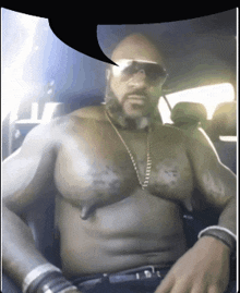 a shirtless man is sitting in a car with a speech bubble above him