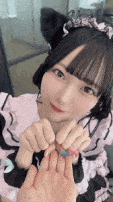 a girl wearing a cat ear headband and a pink dress holds her hands together
