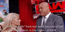 a man in a suit and tie is talking to a woman in a wrestling ring .