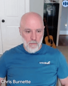 a bald man with a beard is wearing a blue shirt with the name chris burnette on the front