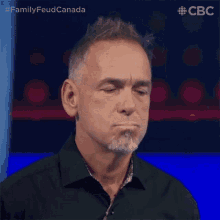 a man with a beard and a black shirt is making a funny face .