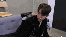 a young man is sitting on a couch in a room with a chair .