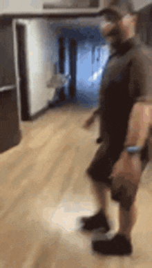a man is standing on a wooden floor in a room .