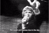 a man singing into a microphone with the words " the moon ain 't gonna rise in the sky " next to him