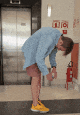 a man in a blue shirt is bending over in front of a fire extinguisher with the number 1 on it