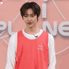 a young man wearing a red vest that says boys planet