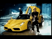 a man is standing next to a yellow sports car with the doors open .
