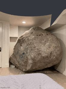 a large rock sits in a room next to a white blanket