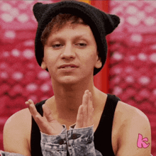 a man wearing a cat ear hat and a denim jacket has a pink k tattoo on his arm