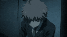 a young boy in a suit and tie is standing in a dark room .