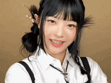 a girl with black hair is smiling and wearing a white shirt