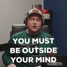 a man wearing headphones singing into a microphone with the words " you must be outside your mind " above him