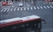 a red and white bus is driving down a street with btv written on the bottom right