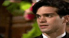 a close up of a man 's face with a woman in a green dress in the background