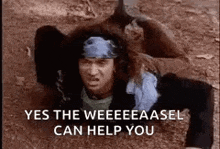 a man with a bandana on his head is laying in the dirt .