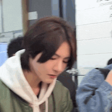 a close up of a person wearing a hoodie and a green jacket