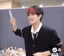 a young man with red hair and a black jacket is holding a toothbrush .