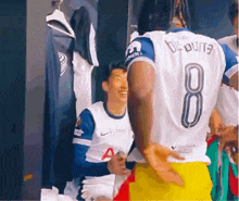 a man wearing a number 8 jersey is standing next to another man