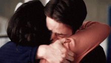 a man and a woman are hugging each other and the woman is kissing the man on the cheek .