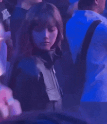 a woman in a black leather jacket is standing in a crowd of people at a party .