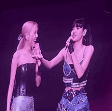 a couple of women standing next to each other on a stage holding microphones .