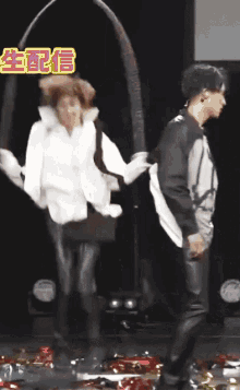 a couple of people dancing on a stage with chinese writing behind them