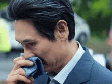 a man in a suit wipes his face with a blue cloth
