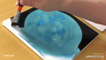 a person is painting a blue moon on a piece of paper that says made in animatica